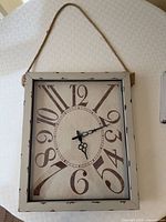 Front view of rectangular wooden wall clock with rope hanger
