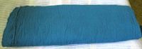 Full bolt of teal gauze fabric on surface