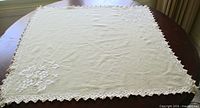 Full view of square table topper showing lace border and embroidery placement