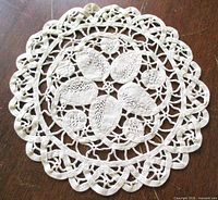 Full view of circular ecru Battenburg lace doily