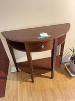 Front view of brown demilune console table showing drawer and shelf