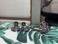 Ring and pair of screw-back earrings with amethyst stones on patterned surface