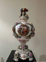 Front view showing painted scene, bird finial, applied flowers, overall form