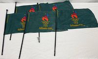 Five green handheld Atlanta 1996 Olympic flags with black sticks laid out