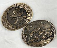 Front view of both brass buckles showing NRA eagle design and waterfowl scene