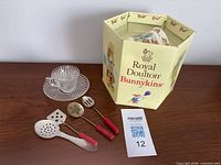 Group shot showing Bunnykins boxed set, glass cup and saucer, and four red-handled metal spoons
