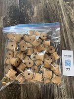 sealed plastic bag containing many small wooden spools