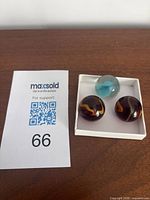 Three large vintage marbles in white display box on wooden surface