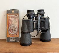 Binoculars standing beside packaged compass