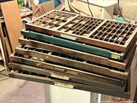 Stack of seven wooden type cases showing fronts with pulls and labels