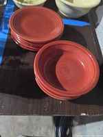 Stack of eight burnt orange Fiesta plates and three matching bowls