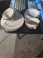 Stacked Lenox cups and plates with Rosenthal pieces beside