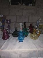 Group shot showing all 10 colored glass vases and pitchers on table