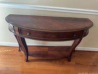 Front view of demi-lune console table showing top surface, drawer, legs and shelf
