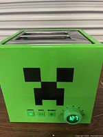 Front view showing Creeper graphic, dial, and control buttons