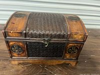 front view of wooden chest showing latch, rattan panel, coin medallions