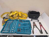 Group shot of all tools laid out: socket set open, bolt cutters, tie-down straps, C-clamp, Voyager bag