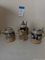 Three steins front view showing sizes, relief designs, pewter lids