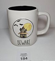 Front of mug showing haunted house graphic and Beware text