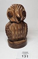 Front view of carved wooden owl eyeglass holder on round base