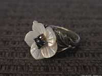 Top view showing carved white flower and dark stone centre on ring