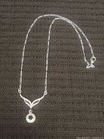 Full view of sterling silver necklace laid flat showing chain length and pendant placement