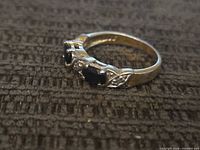 Oblique view of ring showing three dark blue stones and accents