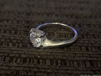Angle view showing sterling silver band and clear solitaire stone in prong setting