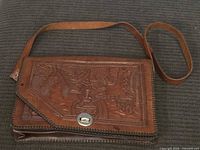 Front view of embossed leather purse showing design and strap
