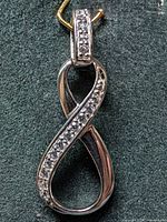 Front view of silver infinity pendant showing CZ stones and bail