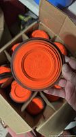 Close-up of single Lawry Precision clay target showing orange face, black rim and embossed branding