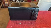 Front view of Panasonic black microwave on red quilted surface