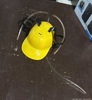 Top view of yellow plastic drinking helmet showing side mounts and tubing