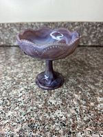 Front view of swirled purple glass compote on pedestal