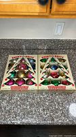 Two boxes of Shiny Brite glass ornaments on countertop