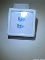 Two pear-cut light blue gemstones in white gem box