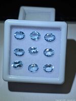 Nine oval light-blue oval gemstones in white gem box