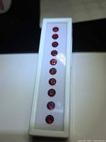 Row of 10 round red gemstones in white display box