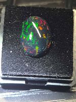 Front view of oval black opal showing multicolour play-of-colour on dark body tone