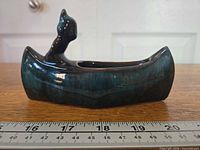 Left side view showing full canoe planter, stamp visible, ruler underneath for scale