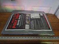 Packaged tarp on table with ruler showing size of package