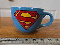 Side view of mug showing Superman logo and scale