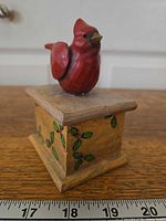 Front view showing carved cardinal on lid and holly motif
