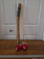 Rainstick and two maracas standing upright for size context.