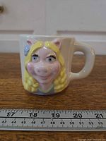Front view of Miss Piggy figural mug with ruler for scale