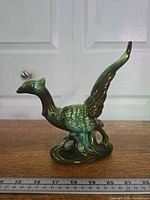 Full view of ceramic pheasant figurine beside ruler for scale