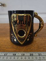 front view showing molded gold planchette, Ouija text and star accents