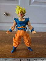 Full front view of figure standing on wooden surface with ruler in foreground