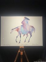 Full view of framed Carol Grigg horse and rider print on easel