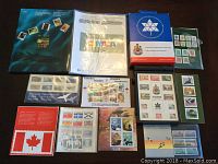 Overview of entire stamp collection including multiple souvenir folders, stamp sheets, and commemorative sets arranged on a table.